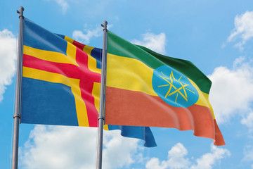Ethiopia and Aland Islands flags waving in the wind against white cloudy blue sky together. Diplomacy concept, international relations.