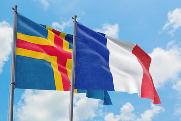 France and Aland Islands flags waving in the wind against white cloudy blue sky together. Diplomacy...