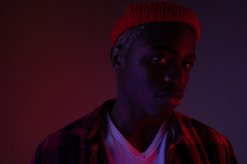 Closeup portrait of a charming handsome black man looking at the camera in neon light in the shade