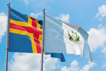 Guatemala and Aland Islands flags waving in the wind against white cloudy blue sky together. Diplomacy concept, international relations.