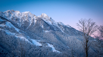 Winter Mountain landscape at the Rosa Khutor ski resort in Sochi, Russia. Silhouettes of trees against a beautiful morning sky in a frosty morning