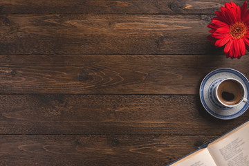 Fototapeta premium Open book, cup of coffee, flower, on wooden background. Flat lay, top view, copy space.