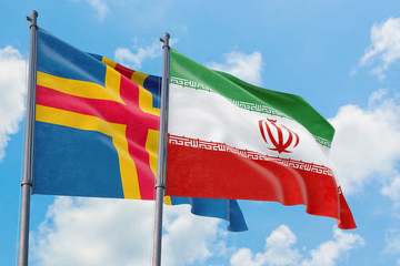 Iran and Aland Islands flags waving in the wind against white cloudy blue sky together. Diplomacy concept, international relations.