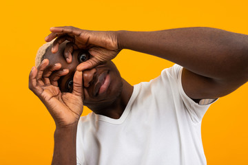 surprised black african young man covers his face with his hands and bulges his eyes