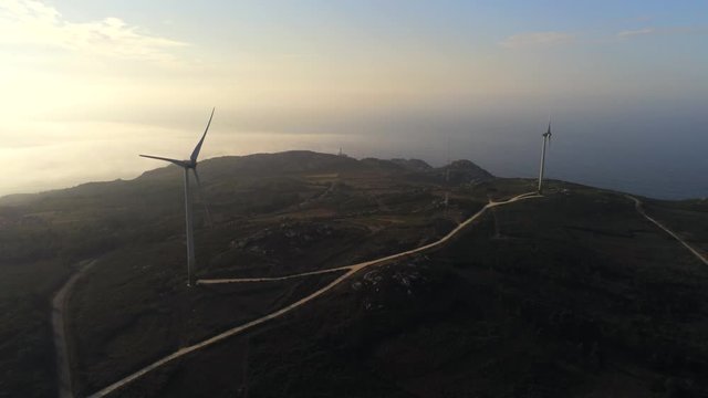Aerial, drone shot, overlooking wind power propellers, on the coast, at sunrise, in A Coruna, Galicia, North Spain