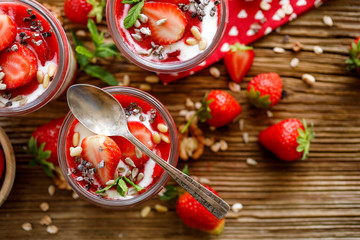 Strawberry-yogurt dessert, healthy dessert with fresh strawberries, natural yoghurt, strawberry mousse and granola on a wooden table, top view. Healthy eating concept