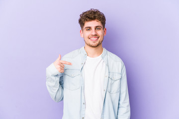 Young blond curly hair caucasian man isolated person pointing by hand to a shirt copy space, proud and confident