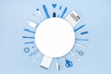 Assorted office and school blue stationery on pastel monochrome background . Flat lay border frame with white round copy space for back to school or education and craft concept