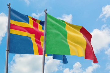 Mali and Aland Islands flags waving in the wind against white cloudy blue sky together. Diplomacy concept, international relations.