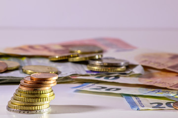 Stapel Euro-Münzen aus 2 Euro, 1 Euro und Cent-Münzen mit einem Haufen Bargeld aus Geldscheinen und EURO-Münzen zeugt von Reichtum in der Finanzwelt und schnelles Geld