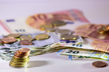 Stapel Euro-Münzen aus 2 Euro, 1 Euro und Cent-Münzen mit einem Haufen Bargeld aus Geldscheinen und EURO-Münzen zeugt von Reichtum in der Finanzwelt und schnelles Geld