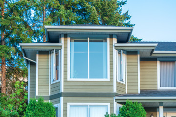A perfect neighborhood. Houses in suburb at Summer in the north America. Top of a luxury house with nice window over blue and white sky.