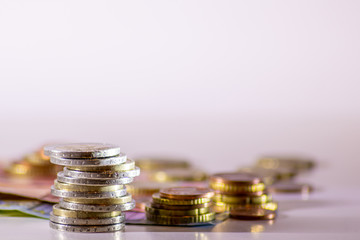 Stapel Euro-Münzen aus 2 Euro, 1 Euro und Cent-Münzen mit einem Haufen Bargeld aus Geldscheinen und EURO-Münzen zeugt von Reichtum in der Finanzwelt und schnelles Geld