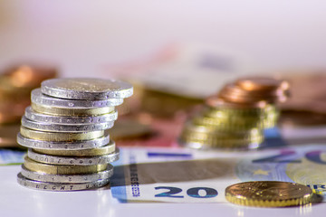 Stapel Euro-Münzen aus 2 Euro, 1 Euro und Cent-Münzen mit einem Haufen Bargeld aus Geldscheinen und EURO-Münzen zeugt von Reichtum in der Finanzwelt und schnelles Geld