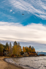 A bird flies over the shore of Lake Tahoe at sunset