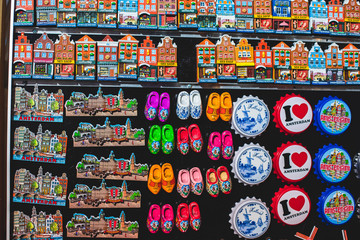 Fototapeta na wymiar Traditional souvenirs from Amsterdam - fridge magnets, rows of Delftware porcelain, Dutch style houses, dutch wooden clogs, wooden tulips and windmill miniature, shop window store front, Netherlands