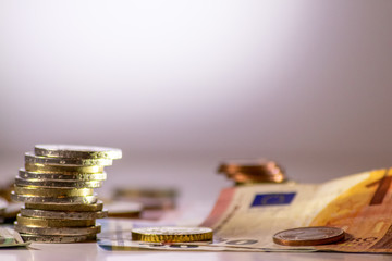 Stapel Euro-Münzen aus 2 Euro, 1 Euro und Cent-Münzen mit einem Haufen Bargeld aus Geldscheinen und EURO-Münzen zeugt von Reichtum in der Finanzwelt und schnelles Geld