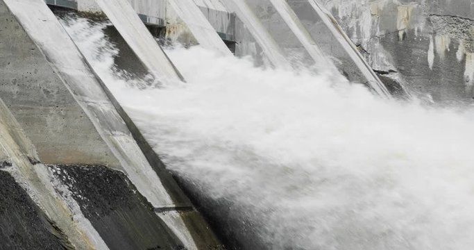 Slow motion shot of powerful water flowing out of a large dam