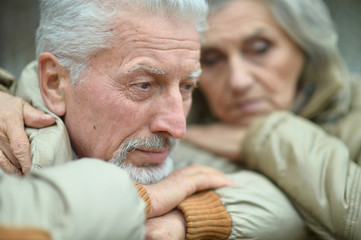 Portrait of sad thoughtful senior couple in park