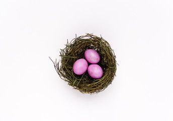 Obraz premium Three pink eggs in a nest, a symbolic representation of easter