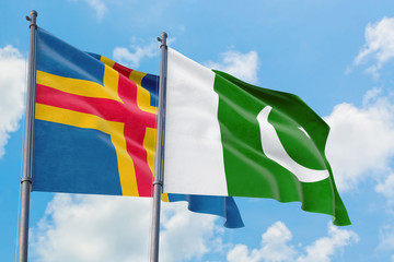 Pakistan and Aland Islands flags waving in the wind against white cloudy blue sky together. Diplomacy concept, international relations.