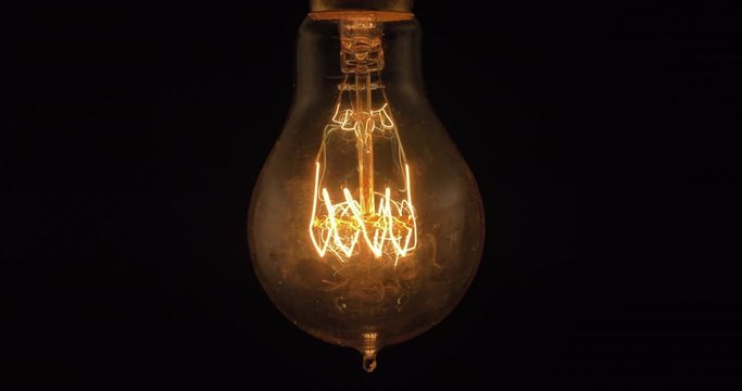 Closeup of a vintage edison lightbulb being switched on and off.