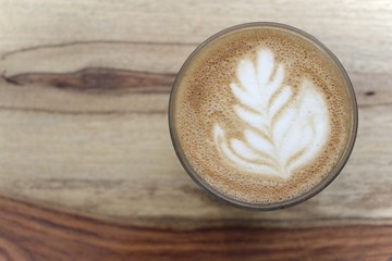 A cup of coffee with latte art, a cappuccino or a moka rich in caffeine with some milk, on the table in a trendy hipster cafe.