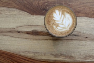 A cup of coffee with latte art, a cappuccino or a moka rich in caffeine with some milk, on the table in a trendy hipster cafe.