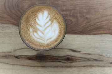 A cup of coffee with latte art, a cappuccino or a moka rich in caffeine with some milk, on the table in a trendy hipster cafe.