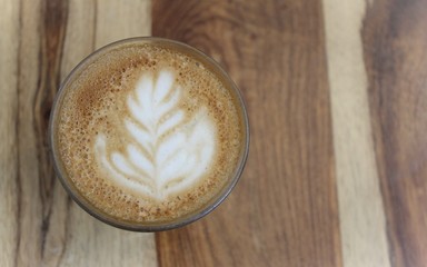 A cup of coffee with latte art, a cappuccino or a moka rich in caffeine with some milk, on the table in a trendy hipster cafe.