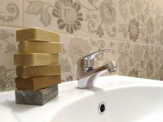 Stack of assorted natural soaps on the sink in the bathroom.