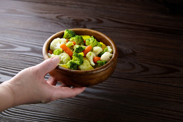 Vegetable mix. Vegan food. Boiled broccoli, cauliflower and carrot in wooden bowl on wooden background. Healthy food. Steamed vegetables