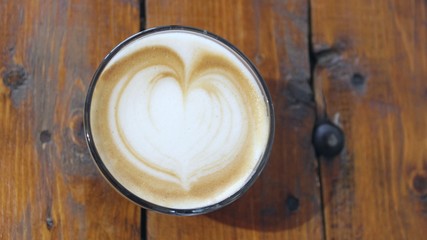 A cup of coffee with latte art, a cappuccino or a moka rich in caffeine with some milk, on the table in a trendy hipster cafe.