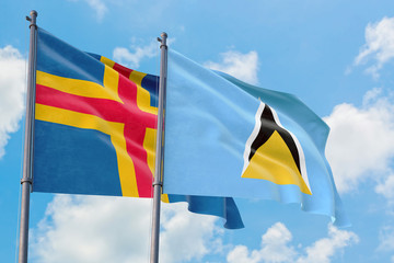 Saint Lucia and Aland Islands flags waving in the wind against white cloudy blue sky together. Diplomacy concept, international relations.