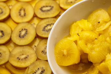 Sliced kiwi with yellow flesh in white  salad dish. Kiwi Gold fruit slices in white bowl on blurred background. Juicy ripe healthy fruit