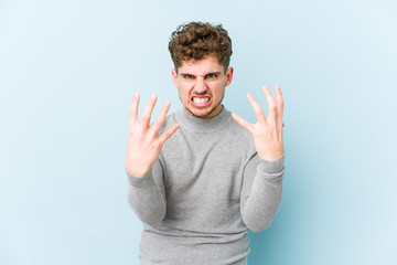 Young blond curly hair caucasian man isolated upset screaming with tense hands.