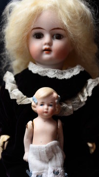 Two beautiful girl dolls, antique toys from porcelain made in Germany, portrayed as two sisters, an older and younger one.