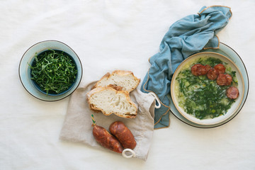 Caldo Verde Soup with greens and chopped chorizo on the top in ceramic bowl.