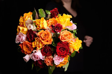 Bouquet of different color roses on a black background. Red, orange and pink flowers. Romantic Valentine's Day Gift