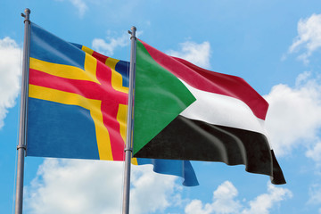 Sudan and Aland Islands flags waving in the wind against white cloudy blue sky together. Diplomacy concept, international relations.