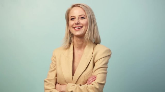 Smiling blonde woman in jacket on blue background