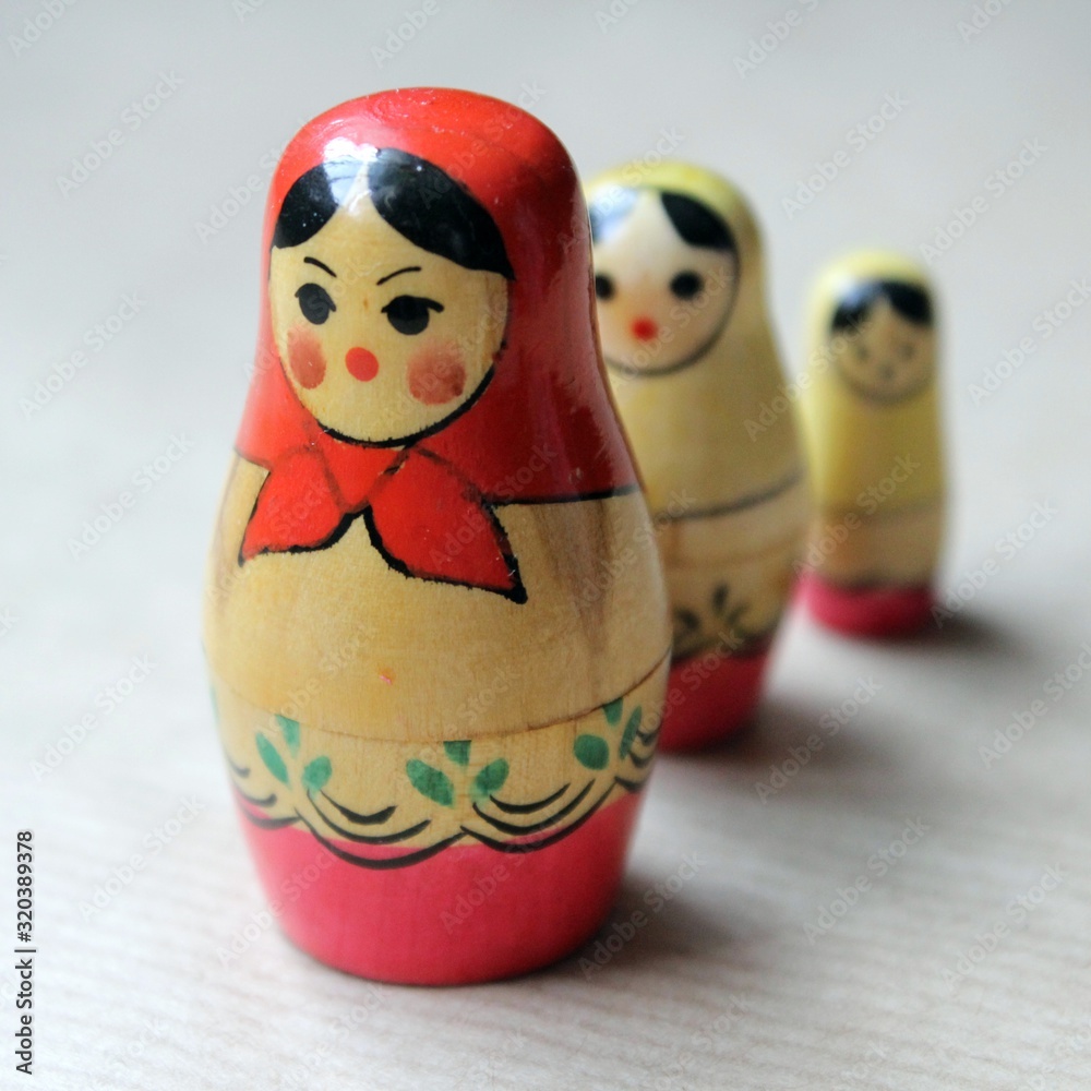 Wall mural Wooden Russian matryoshka dolls in folk style, girls with painted dresses and veiled heads covered with babushka shawl.