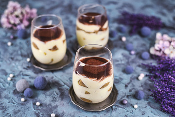 Homemade coffee flavoured layered Italian mascarpone cheese Tiramisu dessert topped with cocoa in glasses