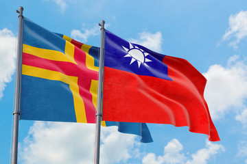 Taiwan and Aland Islands flags waving in the wind against white cloudy blue sky together. Diplomacy concept, international relations.