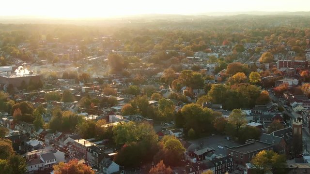 High aerial pullback, aerial city landscape during autumn and dramatic sunset, homes and community establishing shot