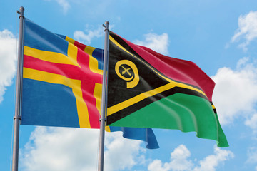 Vanuatu and Aland Islands flags waving in the wind against white cloudy blue sky together. Diplomacy concept, international relations.