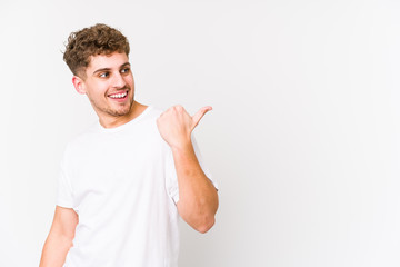 Young blond curly hair caucasian man isolated points with thumb finger away, laughing and carefree.