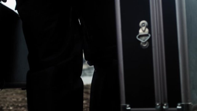 Detective with suitcases walking towards murdered person, crime scene investigation