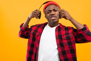 black american man takes off his headphones on a yellow studio background