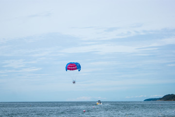 Summer extreme - the boat pulls on the sea behind a parachute with two people. Vacation, happiness, summer, beach